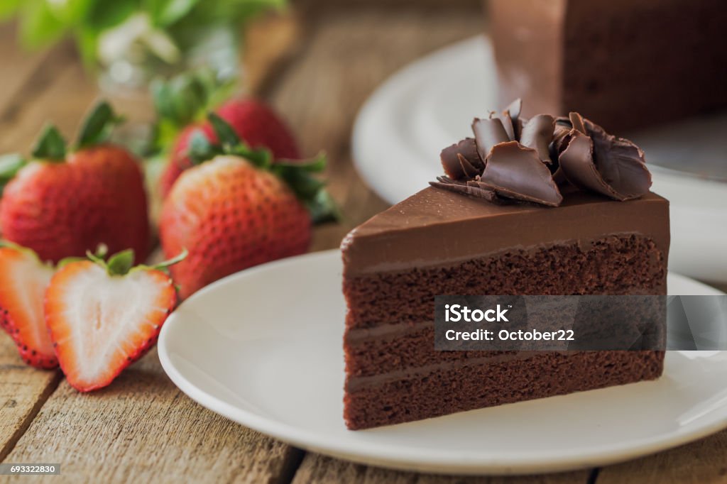 Homemade bakery: chocolate fudge cake decorated with chocolate curl. Triangle slice piece of chocolate cake on rustic wood table for cafe,meeting, coffee break or tea time and birthday party. Cake Stock Photo