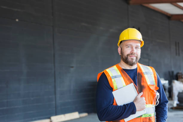 работник в жилете безопасности и hardhat держа цифровой планшет - manual worker portrait helmet technology стоковые фото и изображения