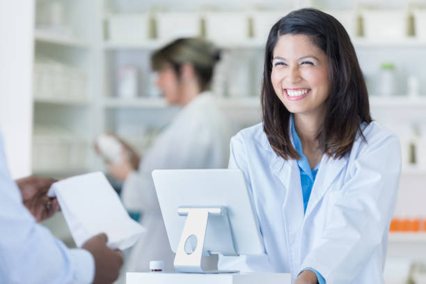 szczęśliwa kobieta farmaceuta rozmawia z klientem przy kasie - checkout counter pharmacy pharmacist patient zdjęcia i obrazy z banku zdjęć