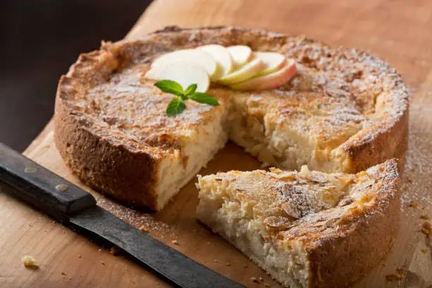 Traditional German Apple Cake on a cutting board with a slice out. (Versunkener Apfelkuchen)