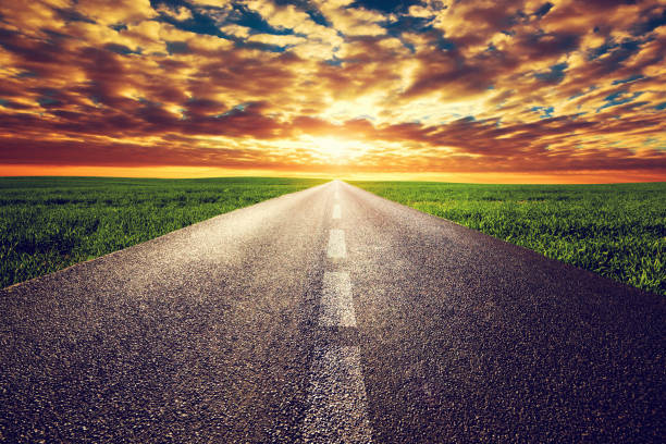 istock Long straight road, way towards sunset sun 693359302