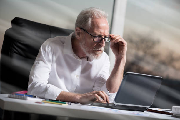 istock Senior businessman working on laptop, light effect, hard light 693363340