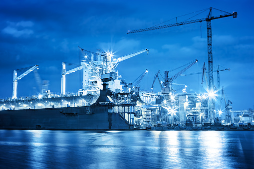 Shipyard at work, ship repair. Industrial machinery, cranes. Transport, freight concept