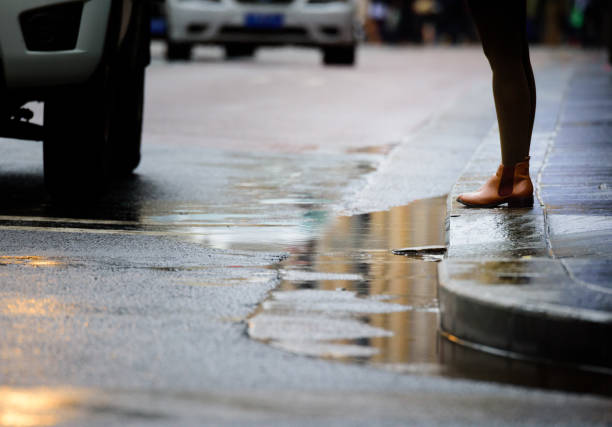 istock Woman standing next to zebra crossing, in rain 693364308