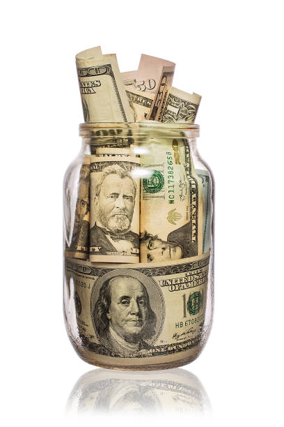 istock Many dollars in a glass jar isolated on white 693370476