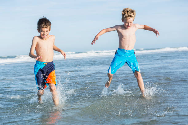 istock Two boys playing in water at beach 693374092