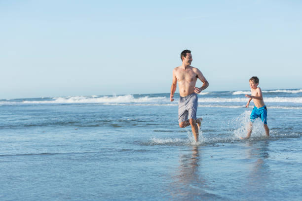 istock Father and son playing in water at beach 693374164