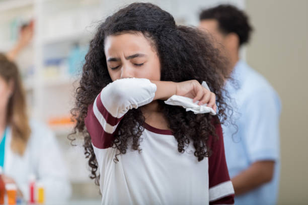 mixed race preteen girl sneezes into her arm - prescription doctor rx pharmacist imagens e fotografias de stock