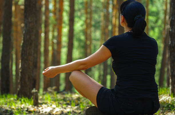 istock A woman meditates in the forest on a sunny summer day 693377584