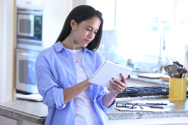 istock A Latina Millennial Working On Her Digital Tablet In Her Kitchen 693388026