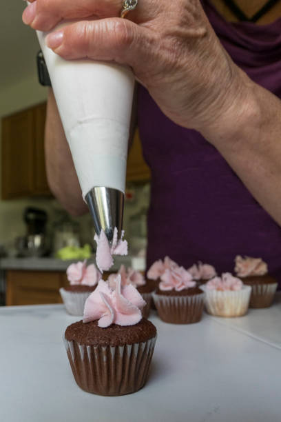 istock Mini Cupcake Decorating at Home by Senior Woman 693401000