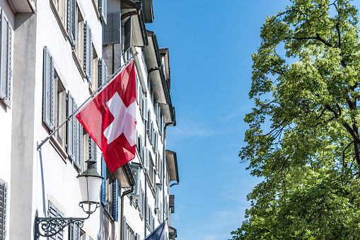 Swiss flag on tall building in Zurich, capital of Switzerland.
