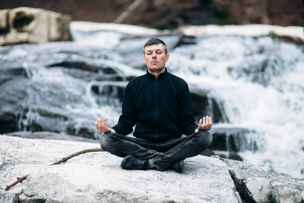 homem meditando em lotus posar na cachoeira - lake tranquil scene landscape zen like - fotografias e filmes do acervo