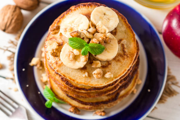istock Pancakes with banana, honey, walnuts and mint on plate. 693421556