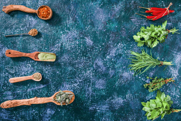 Fresh herbs opposite dried ones Chili peppers, cilantro, tarragon thyme and lemon balm in the forms of fresh herbs and of dried spices  over blue spotty background. Top view tarragon cutting board vegetable herb stock pictures, royalty-free photos & images