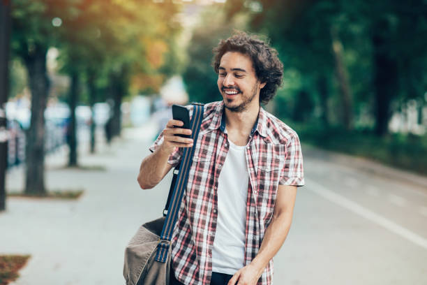 istock Young man walking on the street and texting 693423542