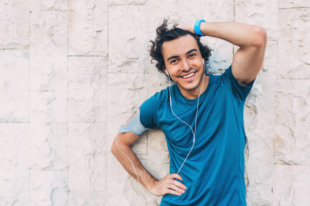istock Smiling athlete at white stone wall background 693423570