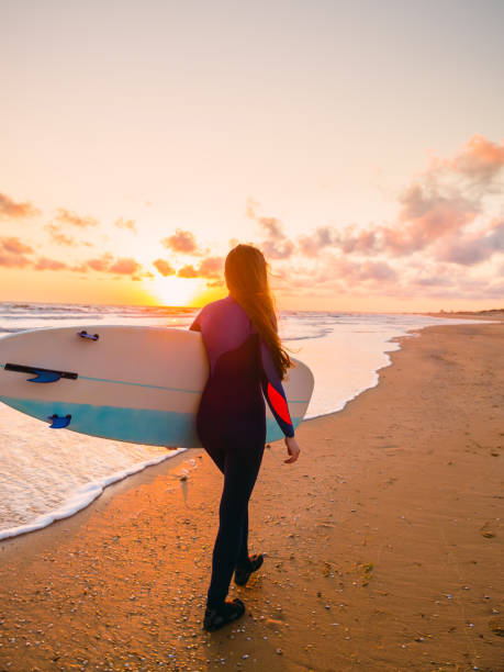 istock Surf girl with surfboard at sunset and ocean in Canada 693425832