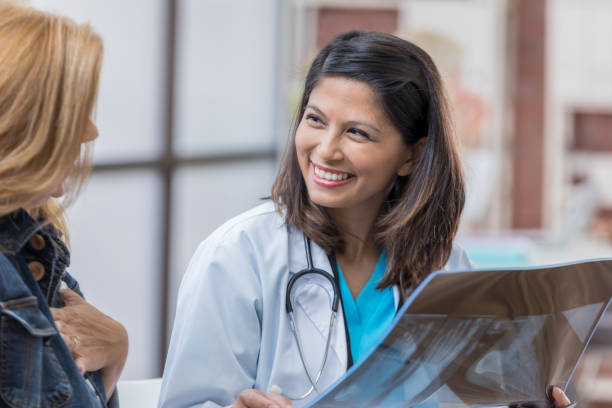 cheerful female doctor discusses x-ray with patient - x ray image radiologist examining using voice imagens e fotografias de stock