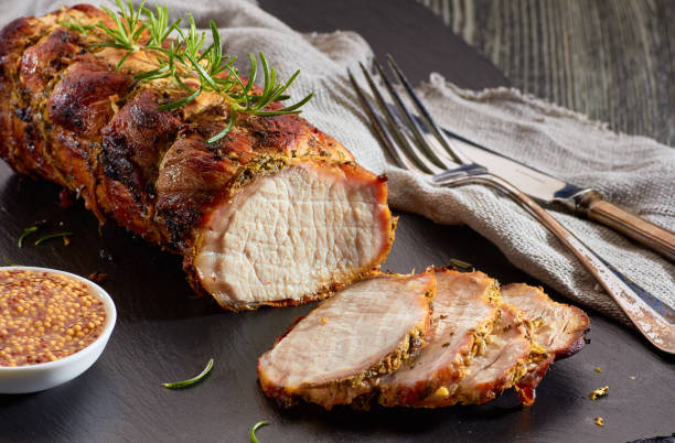 Baked pork loin with whole grain mustard Baked pork loin with whole grain mustard served on black slate roasted stock pictures, royalty-free photos & images
