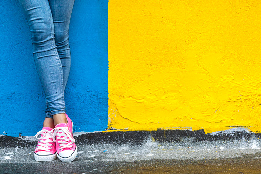 Woman in pink sneakers against yellow and blue wall