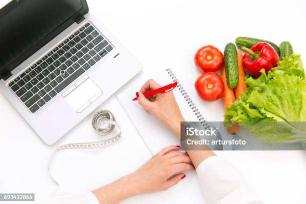 Vegetable Diet Nutrition Or Medicaments Concept Doctors Hands Writing Diet Plan Ripe Vegetable Composition Laptop And Measuring Tape On White Background Stock Photo - Download Image Now
