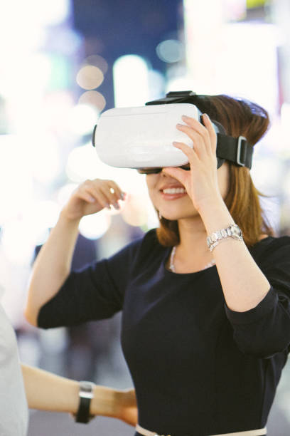 istock Asian woman using virtual reality simulator outdoors 693438986