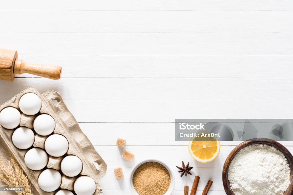 Baking ingredients / cooking food bread pastry or cake Baking ingredients on white wood with copy space. Eggs, brown sugar, white flour, spices and rolling pin on white wooden background. Top table top view. Cooking, baking background, recipe mock up Backgrounds Stock Photo