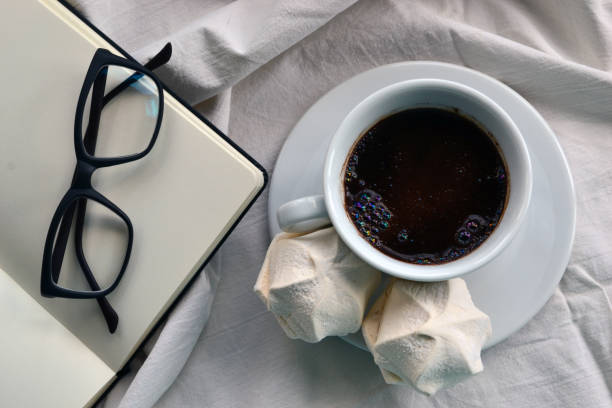 Cup of coffee, notepad and glasses in bed stock photo