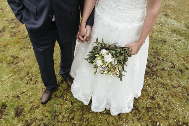 istock Low section of bride and groom holding hands 693475454