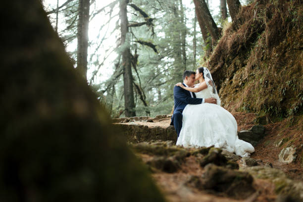 istock Newlyweds sitting on rock and embracing each other 693477754