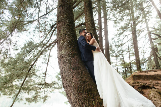 istock Happy newlywed couple embracing next to tree trunk 693477798