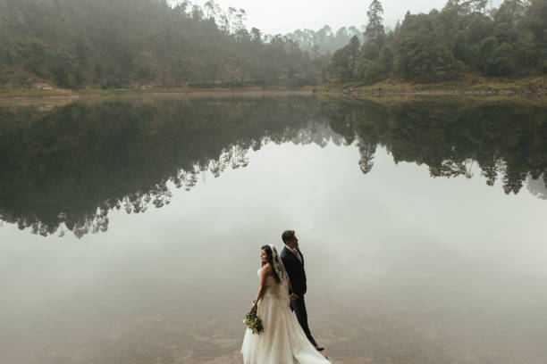 istock Bride and groom couple standing opposite next to lake 693478020