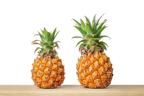 Baby pineapple on wooden table with isolated white background.