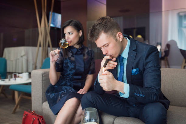 High Society Couple Portrait of an elegant high society couple. Handsome young businessman sitting on the sofa and lighting a cigar while his lady sitting next to him and drinking wine. smoking women luxury cigar stock pictures, royalty-free photos & images