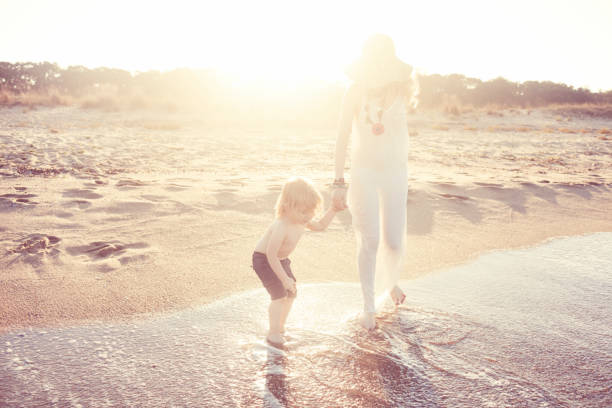Mother and her little son having fun and walking on the beach.