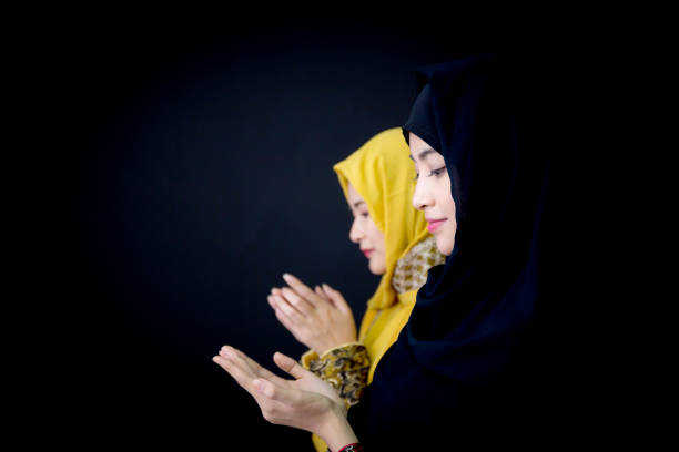 istock religious young Muslim two women praying over black background. 693510002