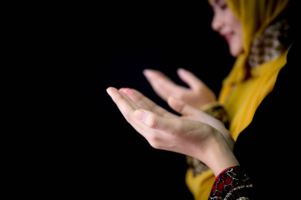 istock religious young Muslim two women praying over black background. 693510030