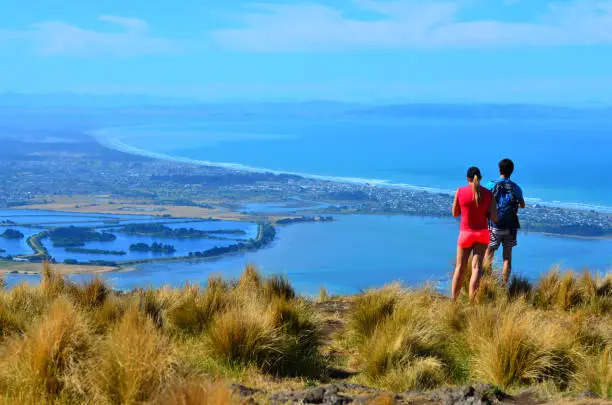 Tourist couple look at the landscape view of Christchurch in Canterbury plains and pegasus bay on the east coast of the south island of New Zealand.