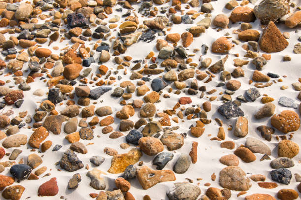 Close-up of smooth round pebble stones on the sand beach backgound