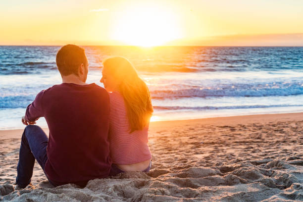 istock Happy Young Couple Sitting on the Beach at Sunset 693547284