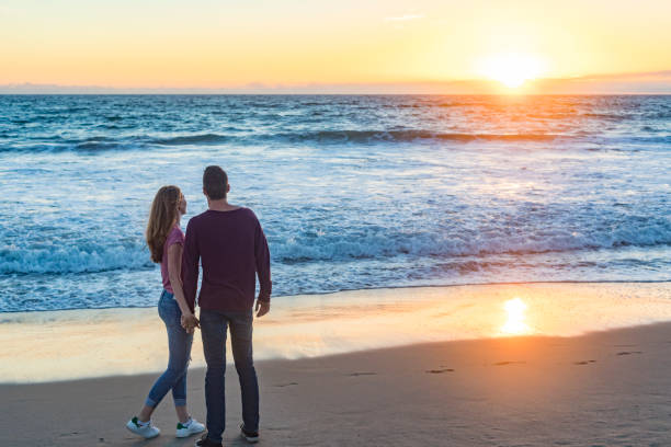 Happy young couple enjoying the sunshine walking at sunset on Venice Beach in Los Angeles, California, USA