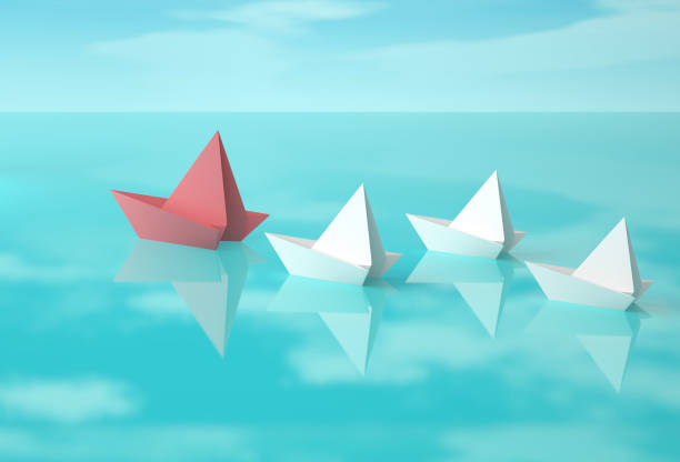 istock Red and white paper boats on water surface 693560082