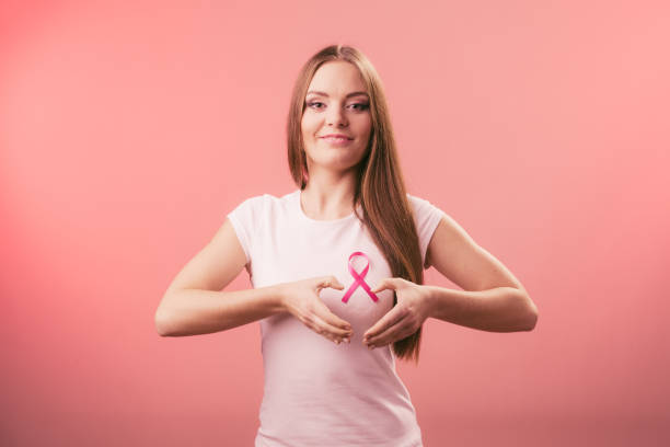Breast cancer. Woman making heart shape on pink ribbon stock photo