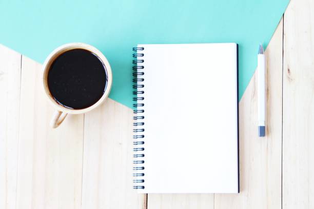 istock Top view image of open notebook with blank pages and coffee cup on wooden background, ready for adding or mock up 693567118