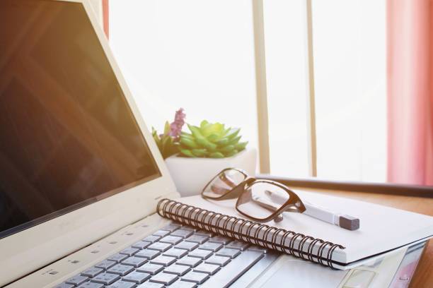 istock Office workplace with laptop, notebook, pen and eye glasses on wood table 693567166