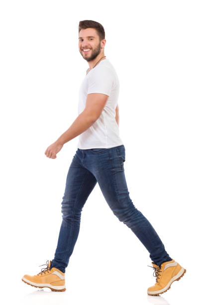 istock Smiling Man In Jeans And White T-shirt Is Walking Side View 693573664