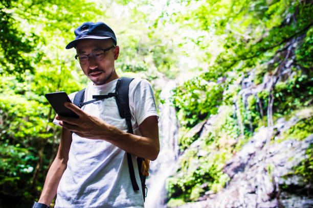 istock Mid adult man using a smart phone in rainforest 693583468
