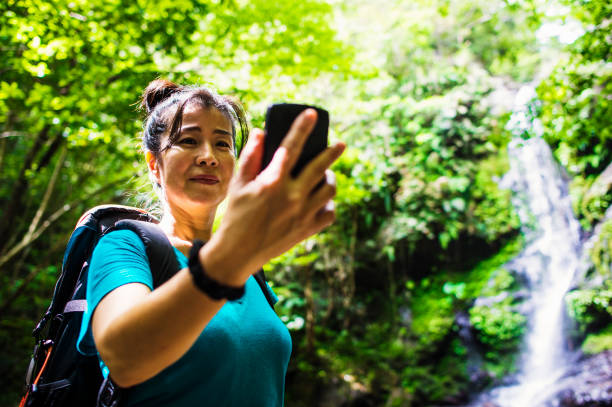 istock Mature woman using a smart phone in rainforest 693583480