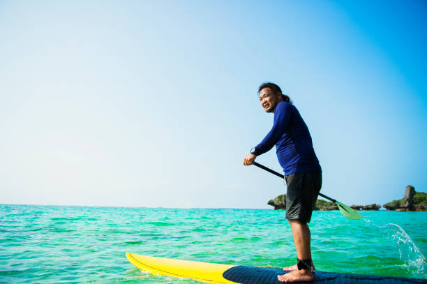 istock Mid adult man having fun with stand-up paddle 693583570